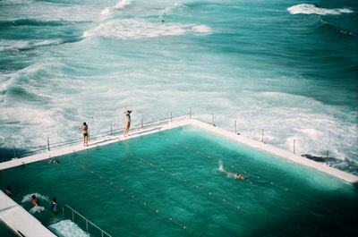 人们站在海边的游泳池里游泳
